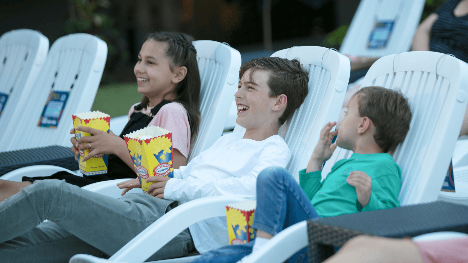 kids at paradise resort watching an outdoor movie with popcorn